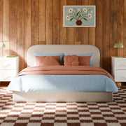 Bedroom with wooden wall, bed with pink and blue bedding, and decorative painting.
